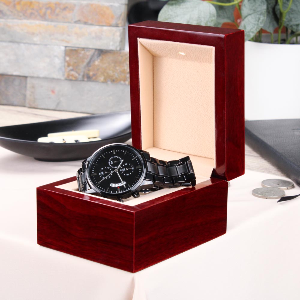 engraved black chronograph watch in a luxurious gift box on a table with a polished surface.